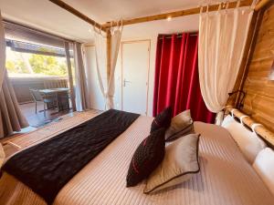sypialnia z dużym łóżkiem z czerwonymi zasłonami w obiekcie Gîte Paradis Lé La w mieście Étang-Salé