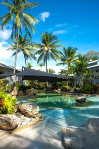 a resort swimming pool with palm trees in the background at Marlin Cove Holiday Resort in Trinity Beach