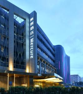 un edificio de oficinas con un cartel en el costado en Mercure Shenzhen Nanshan en Shenzhen
