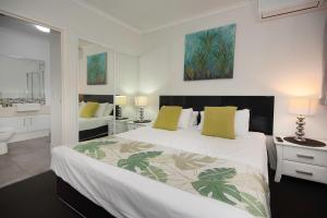 1 dormitorio con 1 cama blanca grande con almohadas amarillas en Marlin Cove Holiday Resort, en Trinity Beach