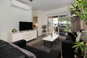 Marlin Cove Holiday Resort في شاطئ ترينيتي: غرفة معيشة مع أريكة وتلفزيون