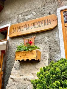 un panneau sur le côté d'un bâtiment avec une boîte de fleurs dans l'établissement Agriturismo La Vecchia Chioderia, à Grandola ed Uniti