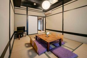 ein Zimmer mit Tisch und Stühlen und einem Fernseher in der Unterkunft Shobu an Machiya House in Kyoto