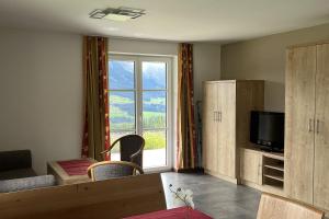 a living room with a tv and a large window at Apartmenthaus Oberlehen in Abtenau