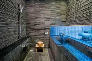 ein Badezimmer mit Waschbecken und Badewanne mit Hocker in der Unterkunft Shobu an Machiya House in Kyoto