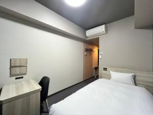 a bedroom with a white bed and a desk and a bed sidx sidx at Hotel Route-Inn Nagaoka Ekimae in Nagaoka