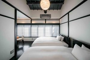 eine Reihe von 4 Betten in einem Zimmer mit Fenster in der Unterkunft Shobu an Machiya House in Kyoto