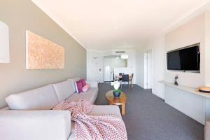 a living room with a couch and a flat screen tv at Sky-high Waterfront Living across Two Apartments in Darwin