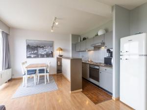 een keuken met een tafel en een witte koelkast bij Apartment on the 8th floor with terrace in Middelkerke +18 foto's