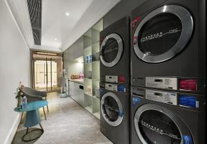 深圳的住宿－深圳南山深圳湾美居酒店，洗衣房配有3台洗衣机和烘干机