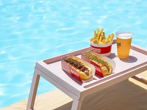 ein Tablett mit zwei Hot Dogs und Pommes Frites und einem Glas Bier in der Unterkunft Latterace Resort in Yeosu