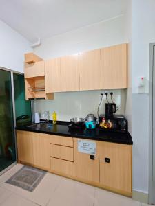 a kitchen with wooden cabinets and a black counter top at Razak City 2 or 3 bedroom KLCC View Sungai Besi, Kuala Lumpur in Kuala Lumpur