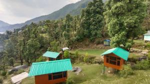 Deux petites maisons aux toits bleus sur une colline dans l'établissement Trekking Cougars Huts, à Dharamshala