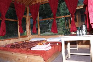 Ce lit se trouve dans un dortoir doté d'une table et de fenêtres. dans l'établissement Trekking Cougars Huts, à Dharamshala