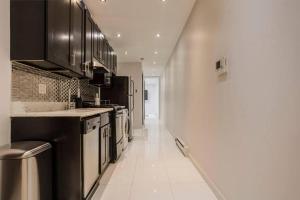 a kitchen with black cabinets and a white tile floor at 5-Bedroom New York Apartment in New York