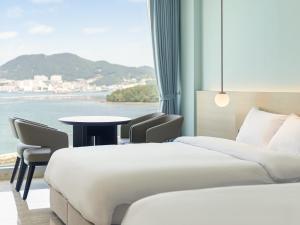 a hotel room with two beds and a table at Yeosu Calacatta Hotel & Resort in Yeosu