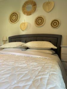 1 cama con sábanas blancas y sombreros en la pared en Grandma Mary's Apartment Nea Playia, en Nea Plagia
