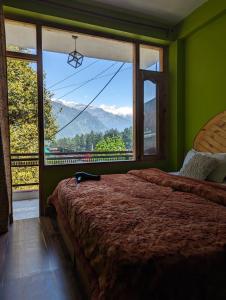 um quarto com uma cama e uma grande janela em Attic Monkey Cafe & Rooms em Manali