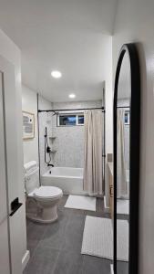 a white bathroom with a toilet and a bath tub at Hoʻonānea I Loko Kailua in Kailua