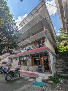 um edifício com uma moto estacionada em frente em Attic Monkey Cafe & Rooms em Manali