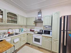 een keuken met witte kasten, een wastafel en een koelkast bij Moncozy guest house in Ulaanbaatar