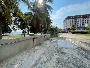an empty street in front of a building with palm trees at 1-10pax DoorStep private beach & swimming pool in Port Dickson