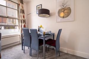 a dining room with a black table and chairs at Seymour Place, Hyde Park, Edgware Road London Apartments in London