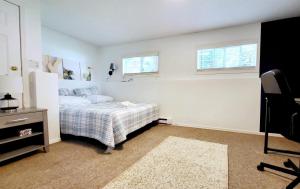 a bedroom with a bed and a desk and two windows at Spacious Vacataion Home in Gorgeous Neighbourhood in Victoria