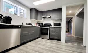 a kitchen with stainless steel appliances and gray cabinets at Spacious Vacataion Home in Gorgeous Neighbourhood in Victoria