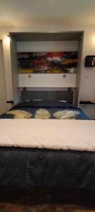 a bedroom with a bed with a painting above it at Le studio de Luce in Cerdon