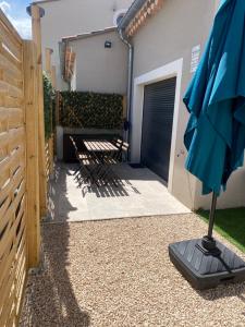 un patio con sombrilla, sillas y una valla en Le Bastidon des Alpilles, en Saint-Étienne-du-Grès