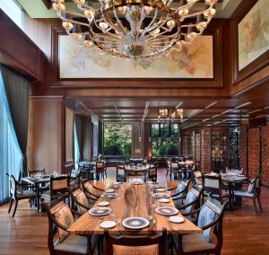 duża jadalnia z dużym drewnianym stołem i krzesłami w obiekcie Sheraton Grand Bengaluru Whitefield Hotel & Convention Center w mieście Bengaluru