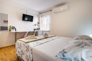 a bedroom with a bed and a tv on the wall at The Rožolina room in Cres