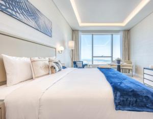 Un dormitorio con una gran cama blanca con una gran ventana. en Palm Tower Stylish Studio02 with Sea View Infinity Pool, en Dubái 11 fotos más