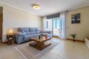 ein Wohnzimmer mit einem blauen Sofa und einem Tisch in der Unterkunft Sunset Seaview Corner With Pool in Estepona