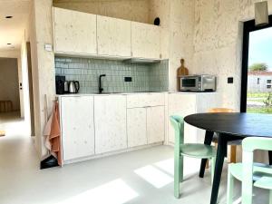 uma cozinha com armários brancos e uma mesa com cadeiras em Hello Zeeland - Tiny House Zeeuwse Liefde 5 em Westkapelle