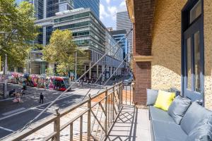 a couch on a balcony with a city street at Tequila Sunrise Hostel Sydney in Sydney