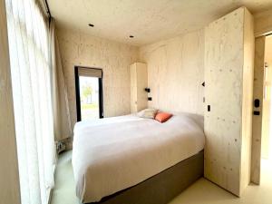 a bedroom with a large white bed with a window at Hello Zeeland - Tiny House Zeeuwse Liefde 5 in Westkapelle