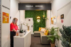a woman standing at a counter in a room with plants at Tequila Sunrise Hostel Sydney in Sydney