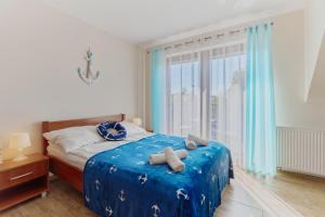 1 dormitorio con cama con sábanas azules y ventana en Villa Konwalia, en Grzybowo