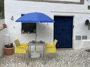 une table avec deux chaises et un parapluie bleu dans l'établissement Estudio Rural el Acebuchal by At Home Costa del So, à Acebuchal