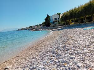 una playa rocosa con una casa en el fondo en Apartmani Afrodita en Sutivan