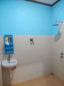 baño con lavabo y pared azul en D'Ru Guest House, en Labuan Bajo