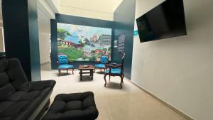 a living room with blue chairs and a tv at HOTEL CATALUÑA - SOLUCIONES HOTELERAs in Pereira