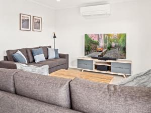 sala de estar con sofá y TV en Snoqualmie 3 2 Cobbodah St, en Jindabyne