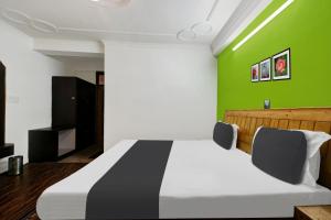 1 dormitorio con 1 cama con pared verde en OYO Asha Cottage, en Manali