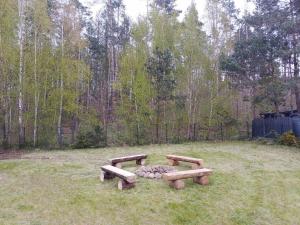 two wooden benches in a field with a fire pit at Dwór pod Sosnami Kaszuby in Ostrzyce