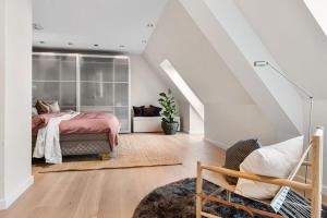 a bedroom with a bed and a chair in a attic at Exclusive Penthouse with Terrace in Bergen