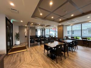 a dining room with tables and chairs and windows at Hotel Route-Inn Toyama Ekimae in Toyama