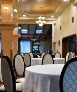 une salle à manger avec des tables et des chaises blanches dans l'établissement Erene Hotel, à Câmpulung Moldovenesc